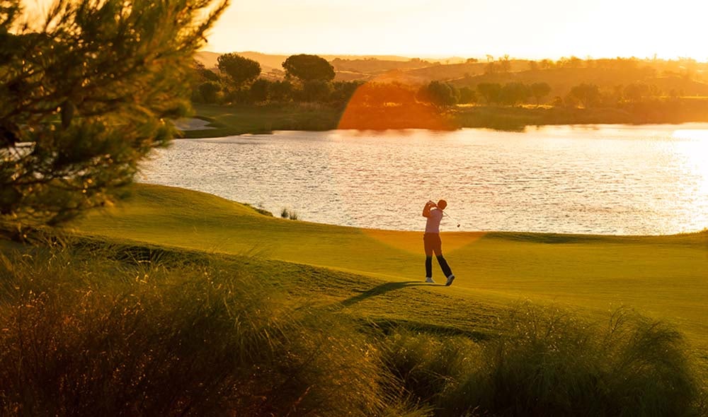 Un golfeur à Monte Rei, au bord du lac dans une lumière dorée