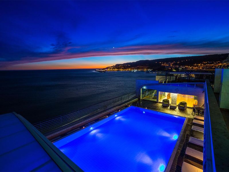 Piscine éclairée pendant la nuit, avec une vue imprenable sur l'océan