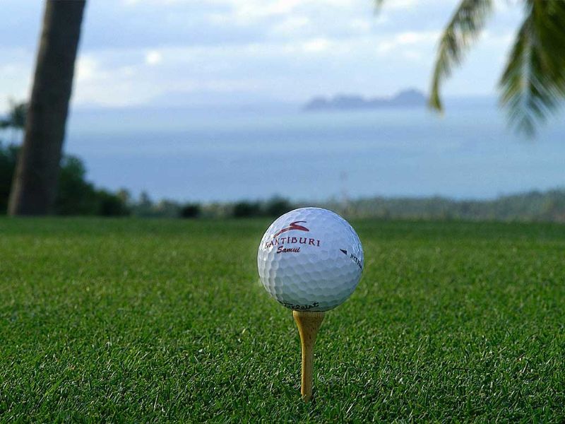 Tee et balle de golf sur le green au bord de l'océan